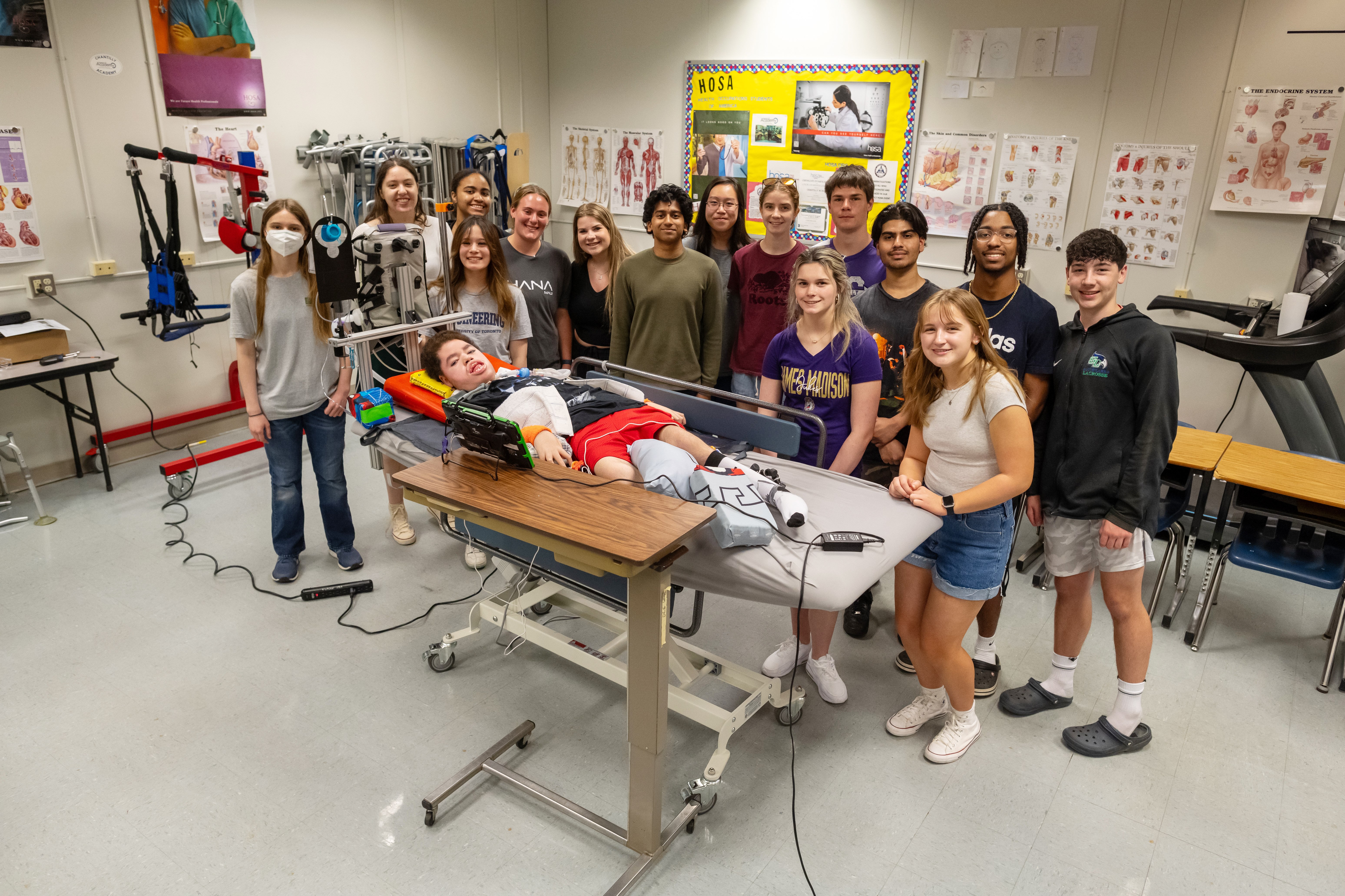 A job well done - the Engineering and PT/OT classes at Chantilly Academy stand with Liam as he tests his new bed.