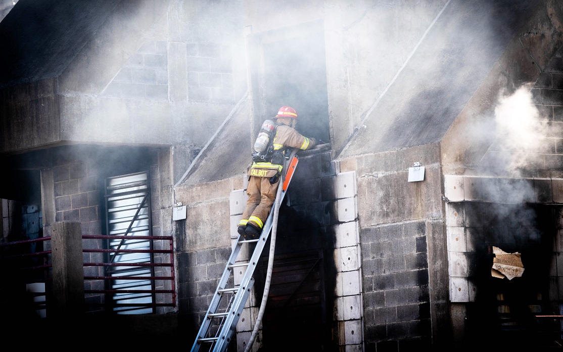 A Fairfax County Fire and Rescue recruit practices battling smoke and fire during a drill.